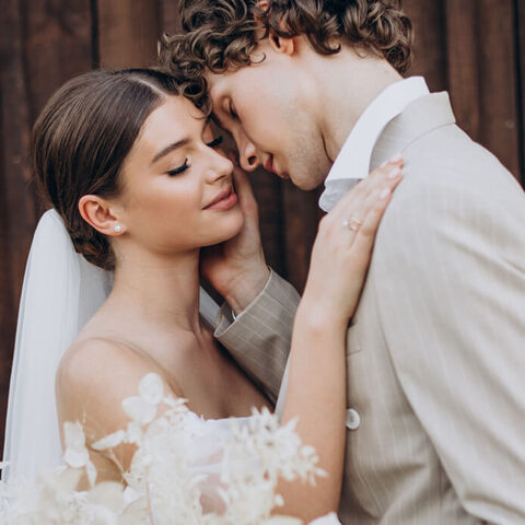 Los novios con las frentes juntas y los ojos cerrados, al aire libre